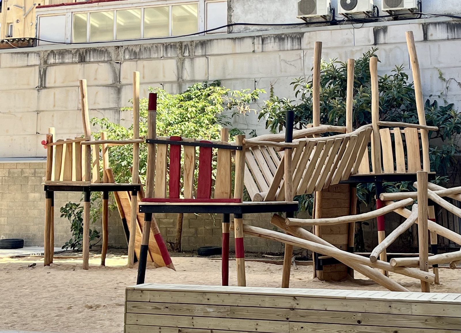 Estructura de joc feta amb troncs, pals i plataformes de fusta sobre sorra.