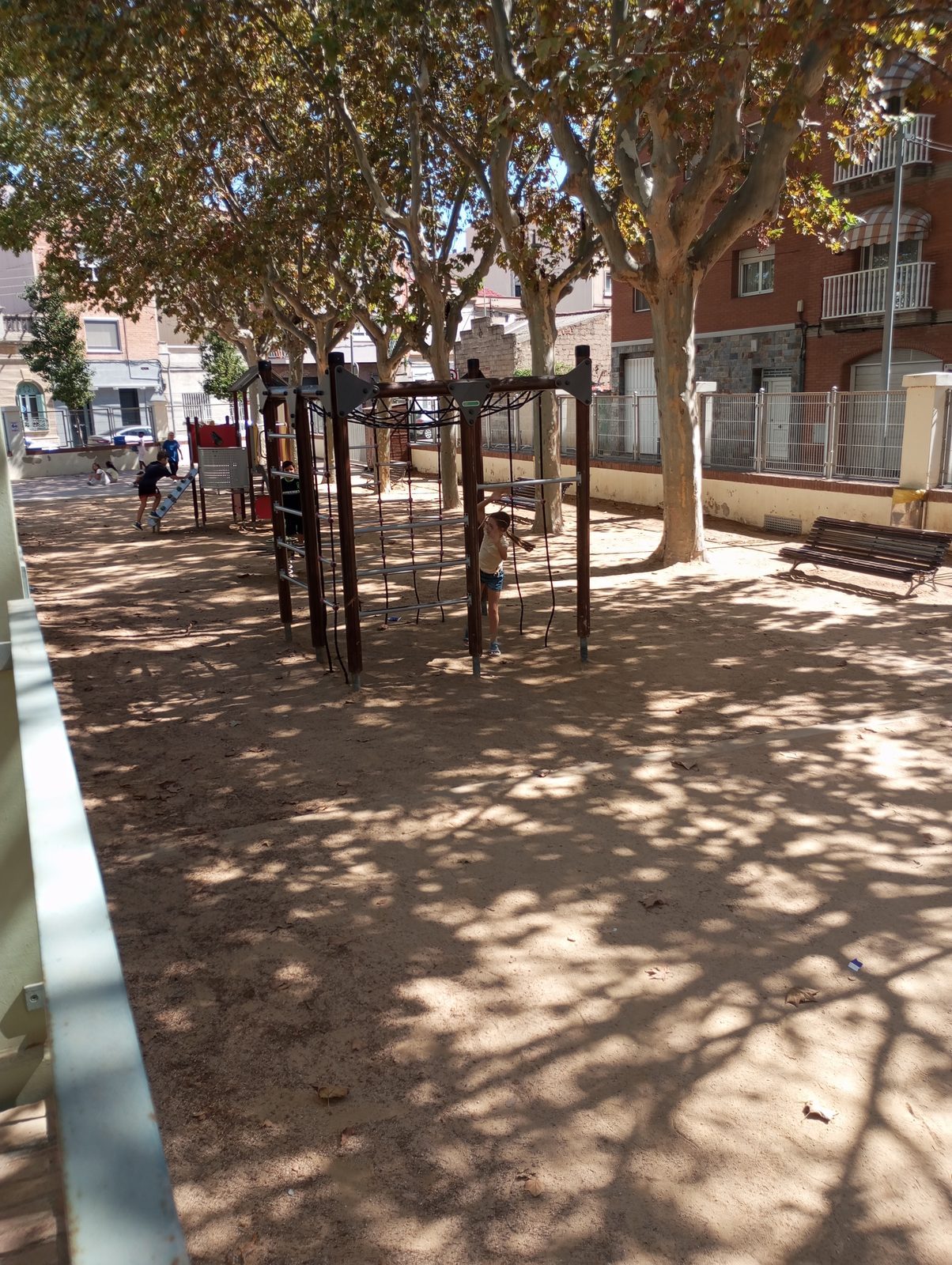 Estructura per enfilar-se en una zona de sorra sota els arbres del pati.