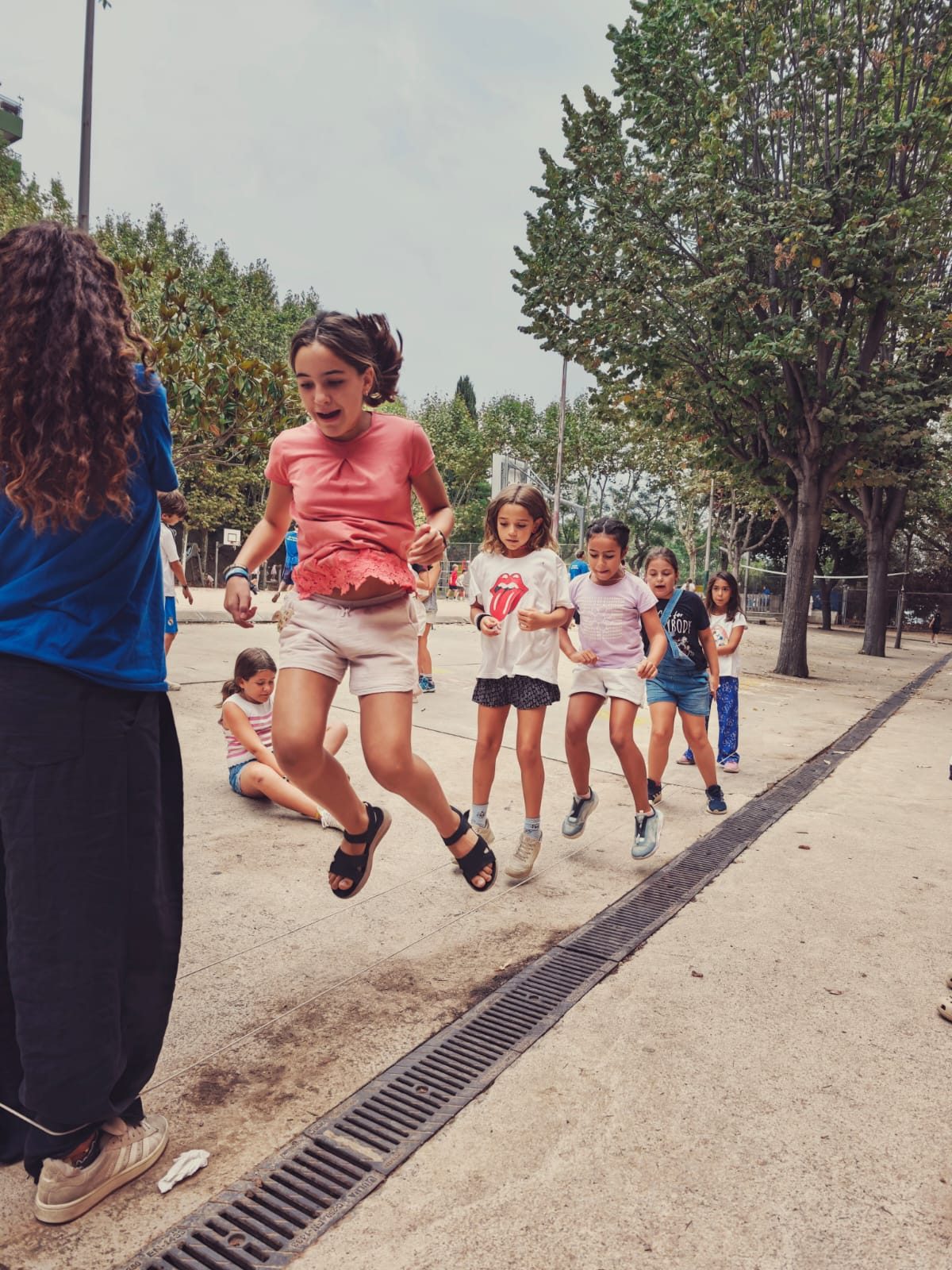 Un grup d’infants corre pel pati acompanyat per una educadora.